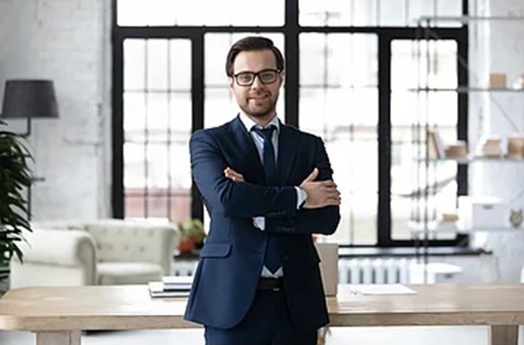 A man in a suit and tie standing with his arms crossed.