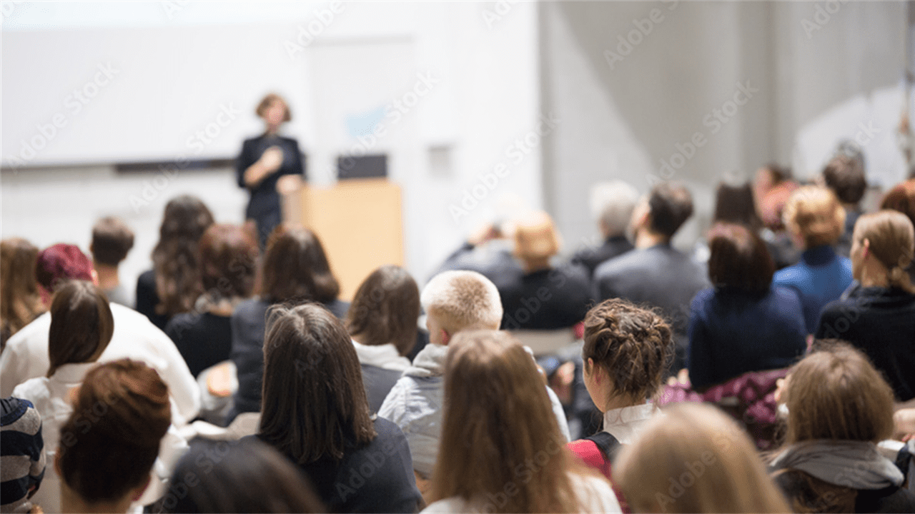 A group of people sitting in front of a speaker.