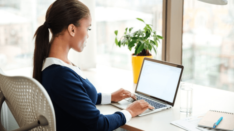 A woman sitting at her desk using a laptop.